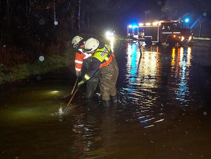 Feuerwehrleute versuchen nach einem Unwetter, mit Pumpen die überflutete Landesstraße 327 bei Montabaur wieder befahrbar zu machen.