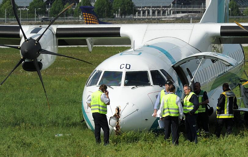 Mitarbeiter des Flughafens in München betrachten die Maschine der italienischen Fluggesellschaft, die am Donnerstag auf dem Münchner Flughafen notlanden musste. Das Flugzeug mit 62 Menschen an Bord hatte kurz nach dem Start in Richtung Venedig umdrehen müssen, weil sich Rauch in der Kabine entwickelt hatte. Bei der Landung wurden fünf Personen leicht verletzt, die Maschine kam neben der Landebahn zum Stehen.