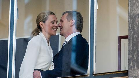 Küsschen links und rechts, eine sanfte Berührung: Christian Wulff hat Bettina Wulff vor dem Prozess in Hannover begrüßt. Medienwirksam vor einem Fenster.