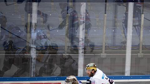 Eishockeyspieler spiegeln sich vor leeren Rängen in der Bande.