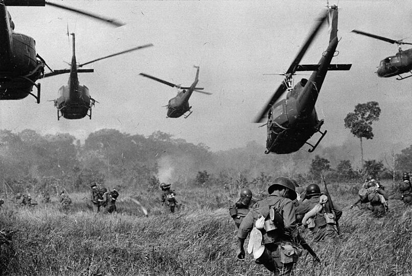 Helicopter der US-Armee schweben im März 1965 in der Luft und halten Maschinengewehrfeuer in eine Baumreihe, um den Anmarsch der Südvietnamesischen Bodentruppen während eines Angriffs auf ein Lager der Vietkong zu decken. Das Foto entstand 18 Meilen nördlich von Tay Ninh.