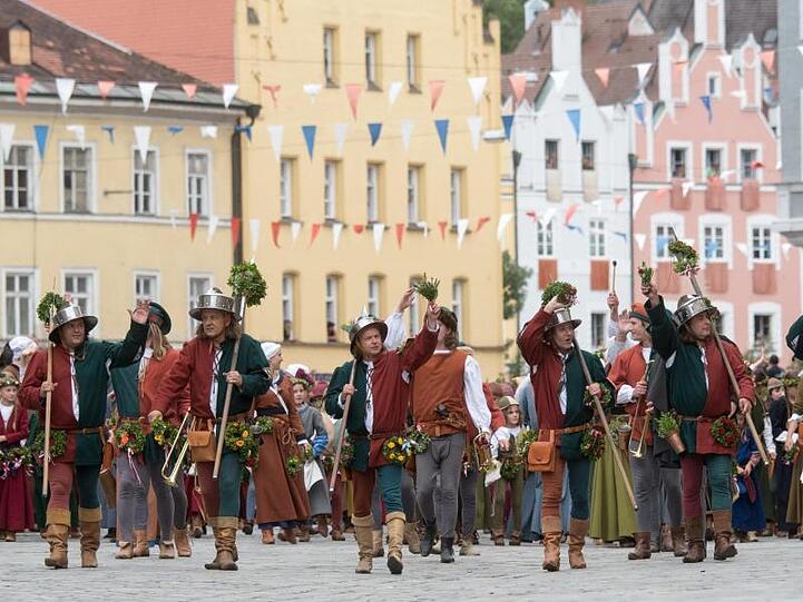 Teilnehmer in historischer Kleidung gehen während dem Umzug der Landshuter Hochzeit durch die Altstadt. Foto: picture alliance / Armin Weigel/dpa/Archivbild