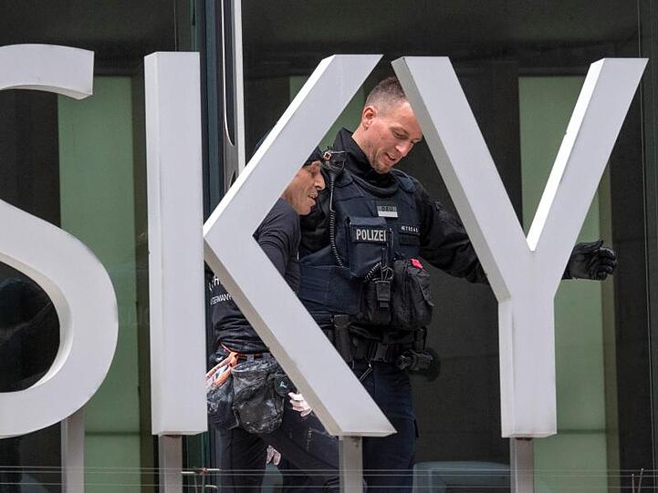 Von einem Polizisten wird der Franzose abgeführt. Sein Kletterausflug stellt eine Ordnungwidrigkeit dar.