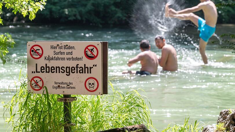 Ein Schild mit der Aufschrift "Lebensgefahr" steht am Ufer des Eisbachs im Englischen Garten. Walzen, Strudel und Unterströmungen machen den Wasserlauf selbst für erfahrene Schwimmer unberechenbar.