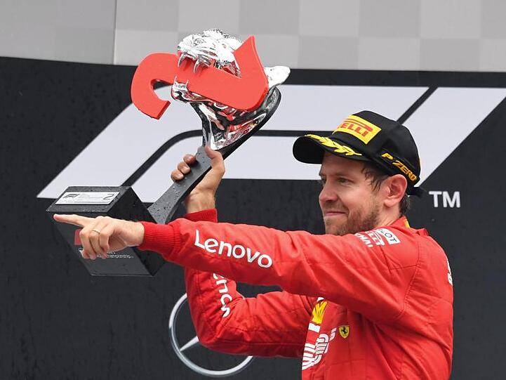Vettel jubelt bei der Siegerehrung mit der Trophäe.