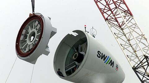Rückblende April 1999: Auf dem windtechnisch günstigen Hügel, 70 Meter über dem umgebenden Gelände, entsteht unmittelbar am Autobahnkreuz Nord Münchens erste Windkraftanlage.