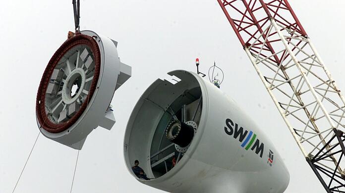 Rückblende April 1999: Auf dem windtechnisch günstigen Hügel, 70 Meter über dem umgebenden Gelände, entsteht unmittelbar am Autobahnkreuz Nord Münchens erste Windkraftanlage.