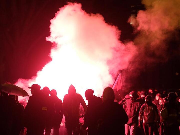 Teilnehmer der linken Demonstration zünden Pyrotechnik.