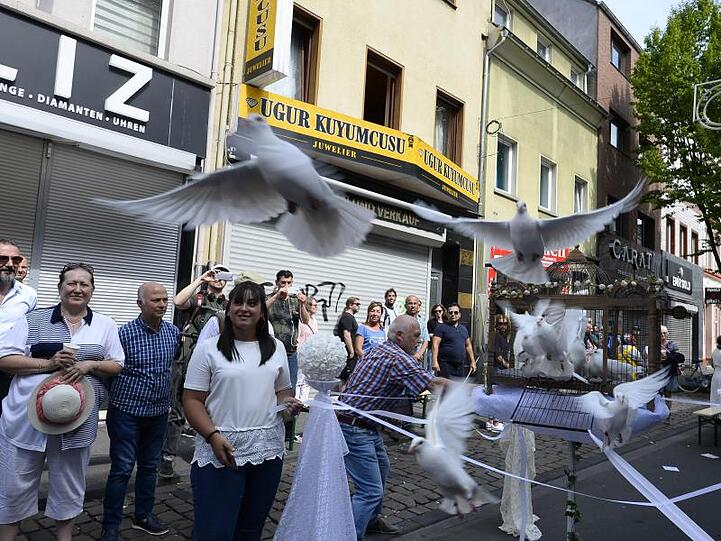 Teilnehmer einer Schweigeminute lassen auf der Kölner Keupstrasse am 15. Jahrestag zur Erinnerung an den NSU-Nagelbombenanschlag, bei dem dort 22 Menschen verletzt wurden, 15 weiße Tauben aufsteigen.