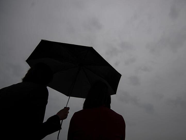Zwei Frauen stehen unter einem Regenschirm. Foto: Marijan Murat/dpa/Illustration