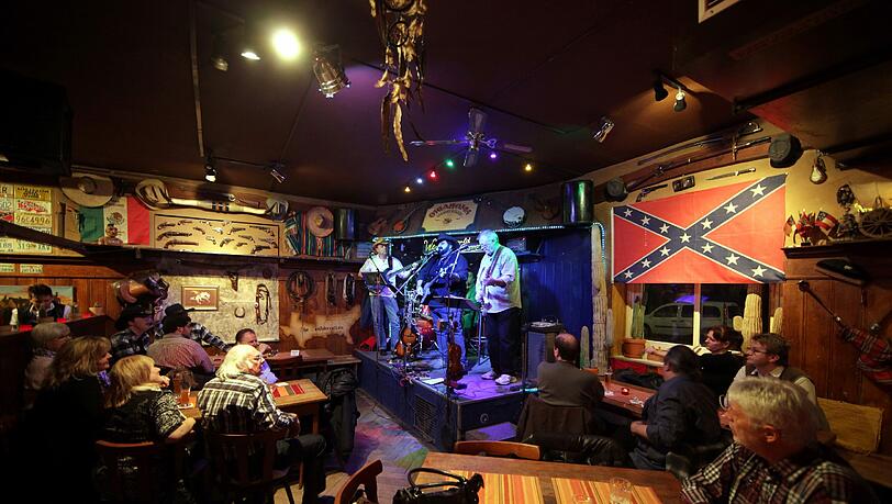 Der Chef steht auf der Bühne, die Sheriff-Hüte wippen mit: Ein Abend im „Oklahoma Saloon“. Der Chef steht auf der Bühne, die Sheriff-Hüte wippen mit: Ein Abend im „Oklahoma Saloon“.
