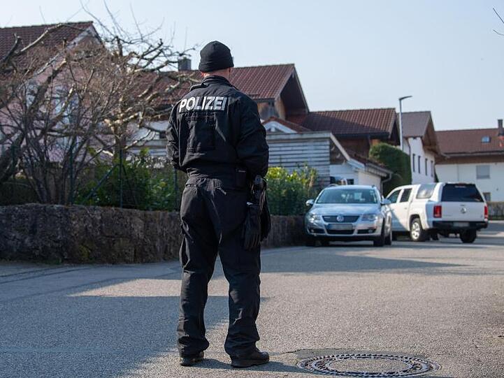 Ein Polizist steht vor einem Haus in Vogtareuth, in dem drei Tote Menschen aufgefunden worden waren. Foto: Lino Mirgeler/dpa/Archivbild