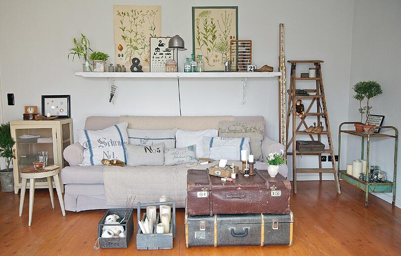 Der Shabby-Stil vermittelt Beschaulichkeit: Alte Koffer werden als Couchtisch verwendet, eine Leiter wird zum Regal.