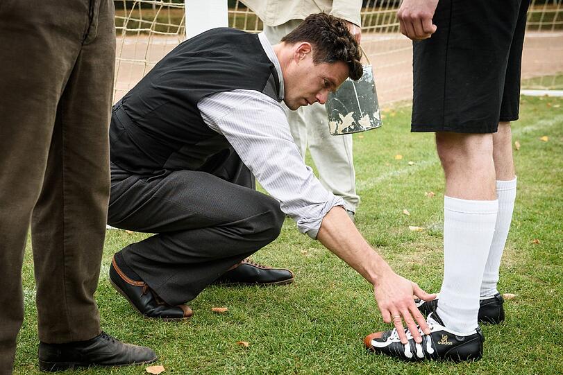Wie ist Adidas zu seinen drei Streifen gekommen? Im Film "Duell der Brüder" wird dazu zumindest eine Legende aufgetischt: Adi Dassler (Ken Duken) streicht mit drei Finger weiße Farbe von einem frisch gestrichenen Torpfosten und verziert einen Schuh damit. Wie ist Adidas zu seinen drei Streifen gekommen? Im Film "Duell der Brüder" wird dazu zumindest eine Legende aufgetischt: Adi Dassler (Ken Duken) streicht mit drei Finger weiße Farbe von einem frisch gestrichenen Torpfosten und verziert einen Schuh damit.