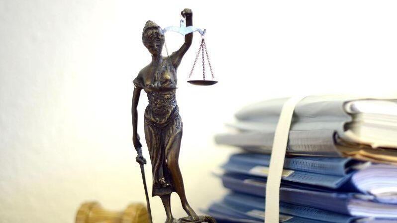Justitia mit Holzhammer und Aktenstapel. Foto: Volker Hartmann/dpa/Symbolbild