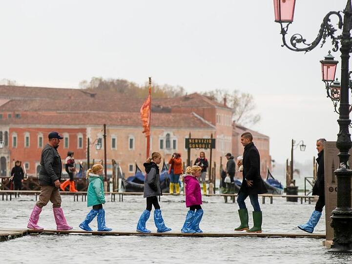 Hochwasser-Routine in Venedig: Touristen sind auf schmalen Stegen unterwegs.