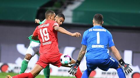 Bremens Jean-Manuel Mbom setzt zum Torschuss an - Augsburgs Torwart Rafal Gikiewicz und Chris Uduokhai versuchen den Ball zu blocken.