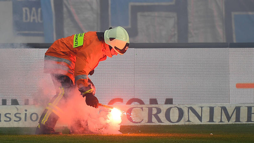 Ein Feuerwehrmann schafft ein Bengalo vom Rasen.