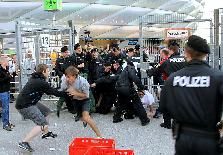 Die Polizei versucht Fans zu stoppen, die durch ein Tor in die Fußball-Arena eindringen wollen.
