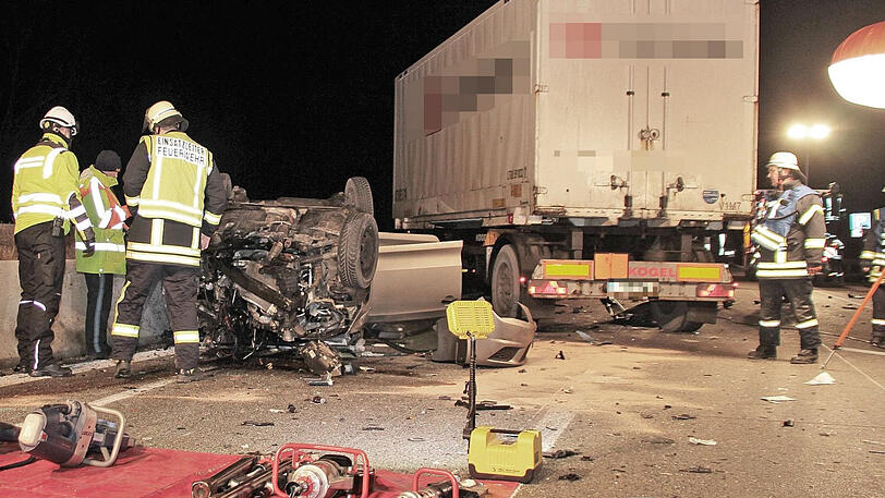 Feuerwehrleute stehen auf der A93 vor dem Autowrack.