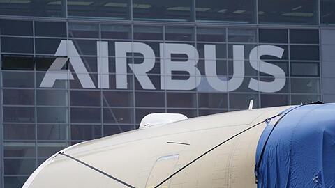 Ein Segment eines Flugzeugrumpfes eines Airbus A350 steht vor einer Fertigungshalle.