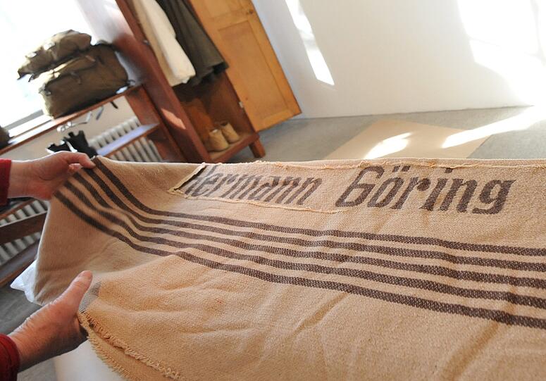Die Decke war für eine Berghütte bestimmt, die aber nie in Betrieb genommen werden sollte. Nach dem Krieg warf man sie nicht weg, sondern überstickte den Namen mit einem Fetzen Stoff.