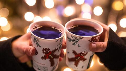 Zwei Frauen stoßen mit Glühwein an.