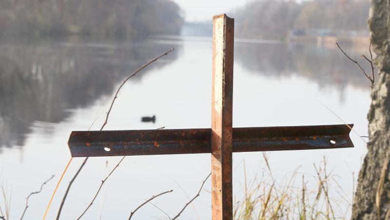 Ein zusammengeschweißtes Metallkreuz steht an einem Gewässer. Foto: Stephanie Pilick