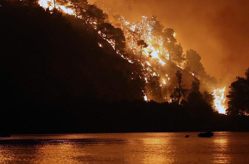 Ein Feuer w&uuml;tet in den W&auml;ldern der griechischen Insel Eub&ouml;a und f&auml;rbt den Nachthimmel im Jahr 2021 orange - es sollte sich um den bis dahin gr&ouml;&szlig;ten Waldbrand in der j&uuml;ngeren griechischen Geschichte handeln.