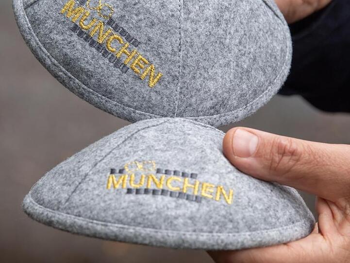Zwei graue Kippot tragen die in gelben Buchstaben gehaltene Aufschrift "München". Foto: Peter Kneffel