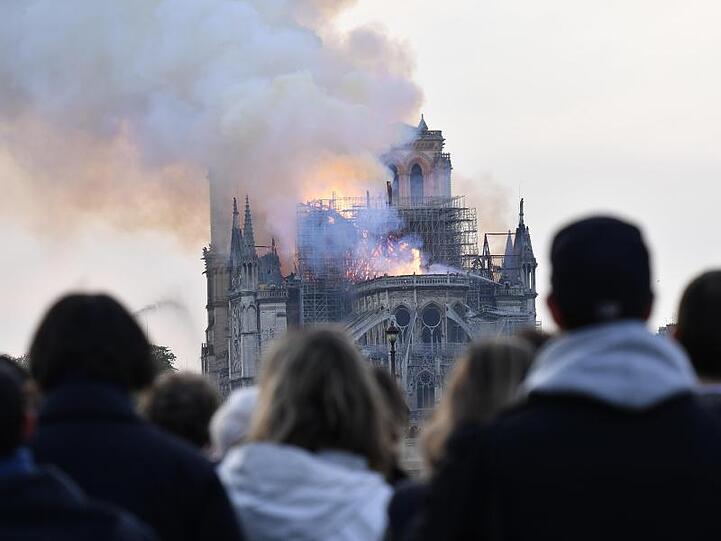 Menschen schauen zum Rauch, der von der Kathedrale Notre-Dame aufsteigt.