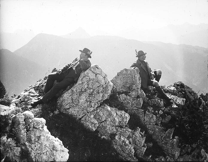 Alpines Stilleben: Zwei Männer mit Hut schauen in die Berglandschaft.