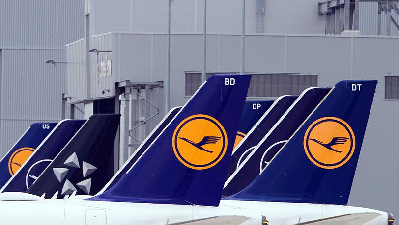 Passagiermaschinen der Fluggesellschaft Lufthansa stehen auf einem Flughafen.