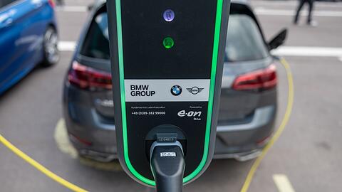 Ein Elektroauto lädt auf einem Parkplatz vor dem BMW-Werk.