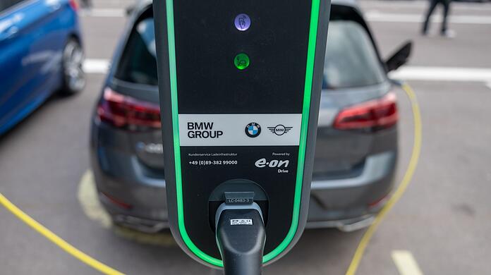 Ein Elektroauto lädt auf einem Parkplatz vor dem BMW-Werk.