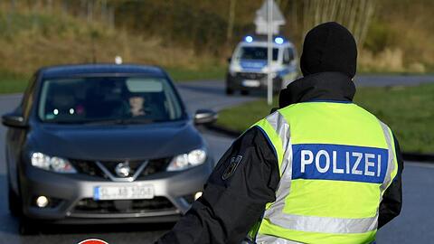 Ein Beamter der Bundespolizei steht an der deutsch-dänischen Grenze an einem Kontrollpunkt.
