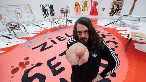 Jonathan Meese, Maler und Aktionskünstler, steht bei einem Interviewtermin in dem noch geschlossenen Ausstellungsraum. Foto: Lino Mirgeler