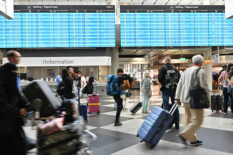 Passagiere am Flughafen M&uuml;nchen mit ihren Gep&auml;ckst&uuml;cken.