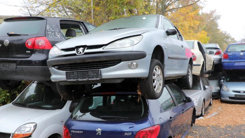 Vor dem Gelände eines Schrottplatzes mit Autopresse stapeln sich alte Autos, vorwiegend Dieselfahrzeuge. Vor dem Gelände eines Schrottplatzes mit Autopresse stapeln sich alte Autos, vorwiegend Dieselfahrzeuge.