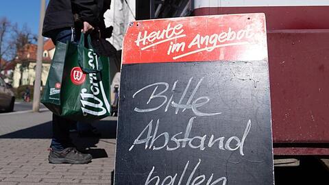 Ein Schild mit der Aufschrift "Bitte Abstand halten" auf einem Wochenmarkt.