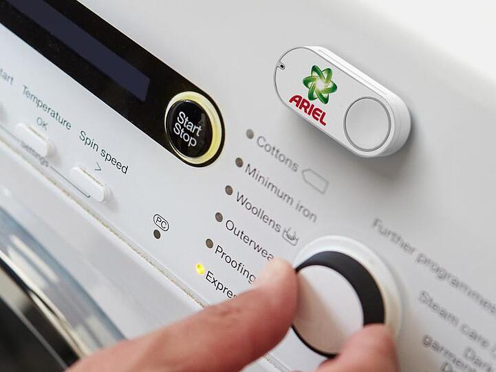 Ein Amazon Dash Button für die Marke Ariel klebt an einer Waschmaschine.