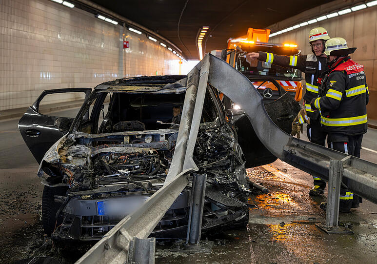 Feuerwehrleute stehen nach einem Fahrzeugbrand im Innsbrucker-Ring-Tunnel um den verungl&uuml;ckten Seat Cupra.