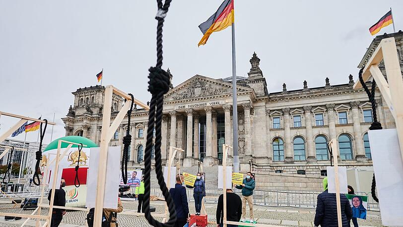 Demonstranten stehen mit symbolischen Galgen vor dem Reichstag und demonstrieren gegen Hinrichtungen und die Todesstrafe im Iran.