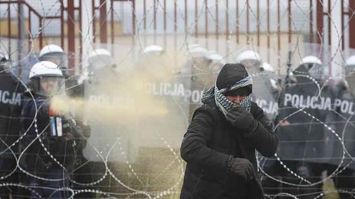 Ein Flüchtling wird von einem polnischen Soldaten mit Tränengas auf Distanz gehlten.