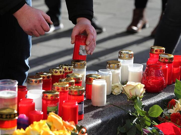 Ein Mann plaziert ein Grablicht an einem Rondell am Königsplatz. Foto: Karl-Josef Hildenbrand/dpa
