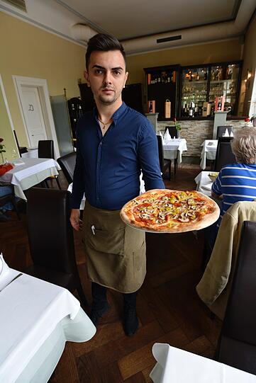 Die Pizza kommt aus dem Holzhofen - und Kellner Alexander bringt sie frisch an den Tisch.