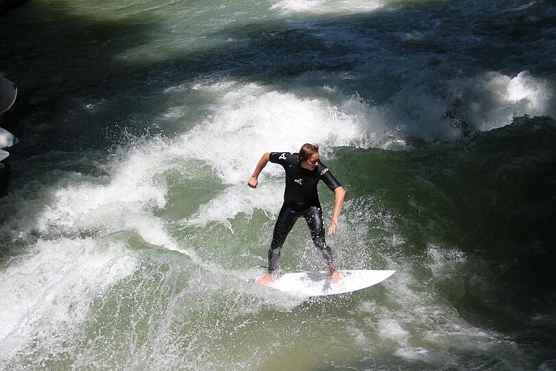 Gehört besonders im Sommer dazu: Eisbachsurfen auf der &bdquo;stehenden Welle&ldquo; am Haus der Kunst.