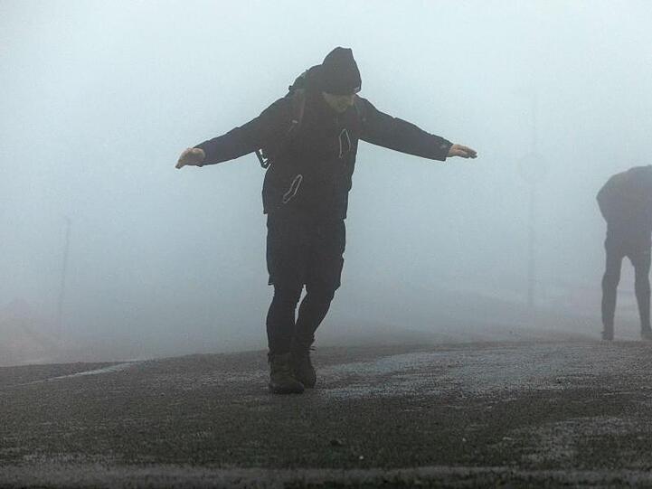 Touristen kämpfen gegen die Windböen auf dem Brocken.
