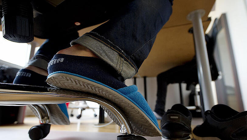 Ein Mitarbeiter eines Internet-Startup's trägt beim arbeiten Hausschuhe. Das unterschätzte Gesundheitsrisiko "Dauersitzen" macht sich auch schon bei den Kindern bemerkbar. (Archivbild) Ein Mitarbeiter eines Internet-Startup's trägt beim arbeiten Hausschuhe. Das unterschätzte Gesundheitsrisiko "Dauersitzen" macht sich auch schon bei den Kindern bemerkbar. (Archivbild)