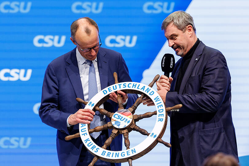 Symbolträchtig: Markus Söder (r., CSU) übergibt Friedrich Merz, Kanzlerkandidat und Vorsitzender der CDU, beim kleinen CSU-Parteitag ein Steuerrad.